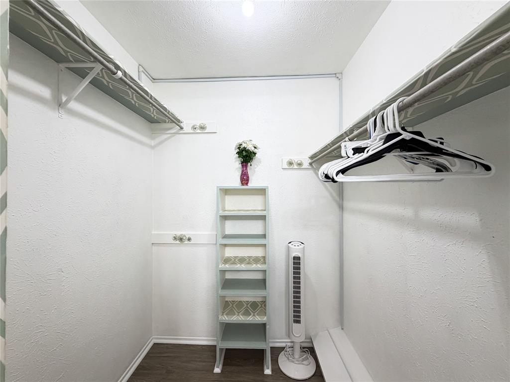 4565 North O'Connor Road, Unit 1304 Irving, TX 75062 - Photo 18 of 32 Primary Walk-in closet featuring dual wall-mounted hanging rods, upper storage shelves with patterned lining, and wood-finish flooring