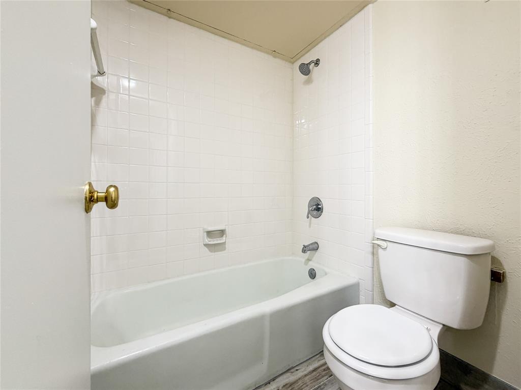 4565 North O'Connor Road, Unit 1304 Irving, TX 75062 - Photo 24 of 32 Bathroom featuring a white porcelain tub and toilet, white subway tile surround, chrome fixtures, and wood-finish flooring
