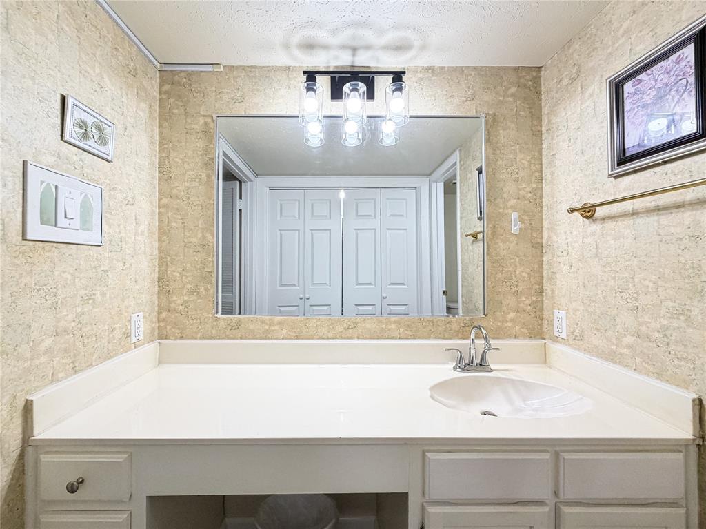 4565 North O'Connor Road, Unit 1304 Irving, TX 75062 - Photo 25 of 32 Vanity featuring a single integrated sink, chrome faucet, and expansive white countertop