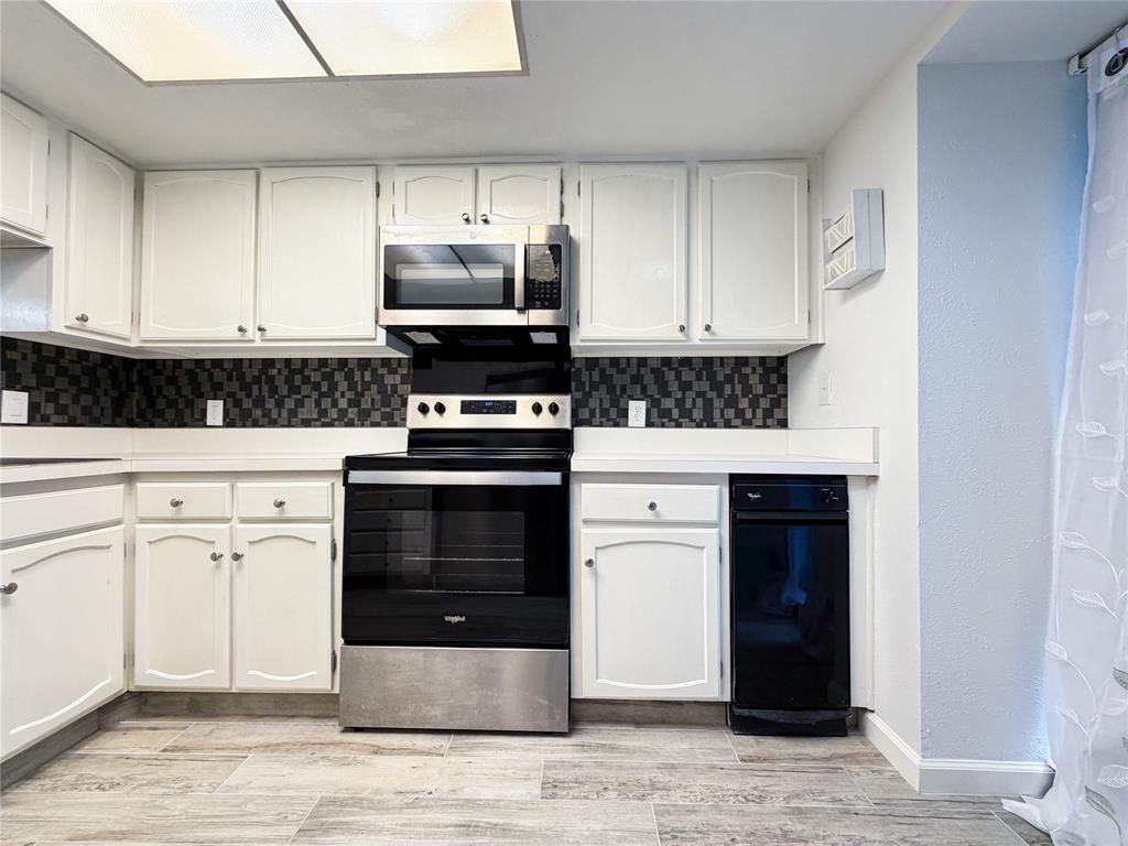 4565 North O'Connor Road, Unit 1304 Irving, TX 75062 - Photo 7 of 32 Contemporary kitchen featuring white cabinetry, a mosaic tile backsplash, light-toned countertops, wood-finish flooring, and a black and stainless steel range