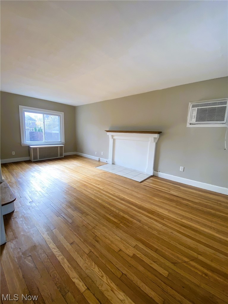 3586 Cedarbrook Road Cleveland, OH 44118 - Photo 5 of 30 Empty room featuring an AC wall unit, radiator, and hardwood / wood-style flooring