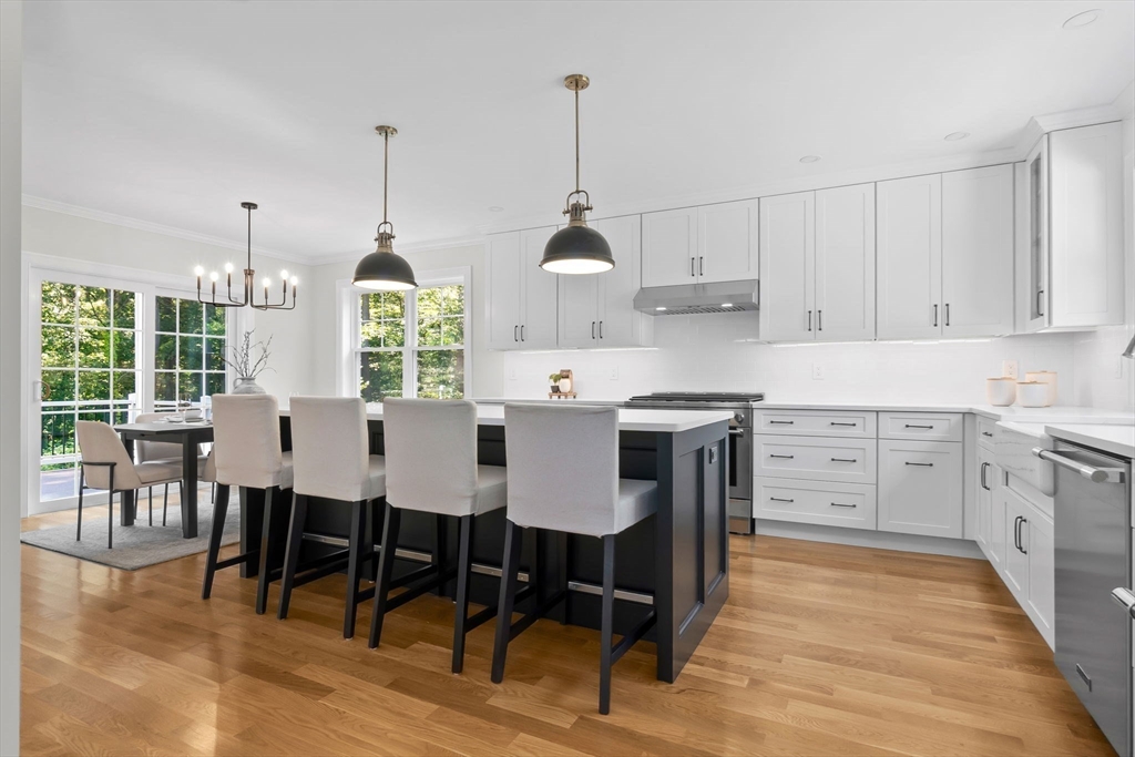 111 Killam Hill Road Boxford, MA 01921 - Photo 9 of 42 a kitchen with stainless steel appliances granite countertop a stove a refrigerator a kitchen island a dining table and chairs with wooden floor