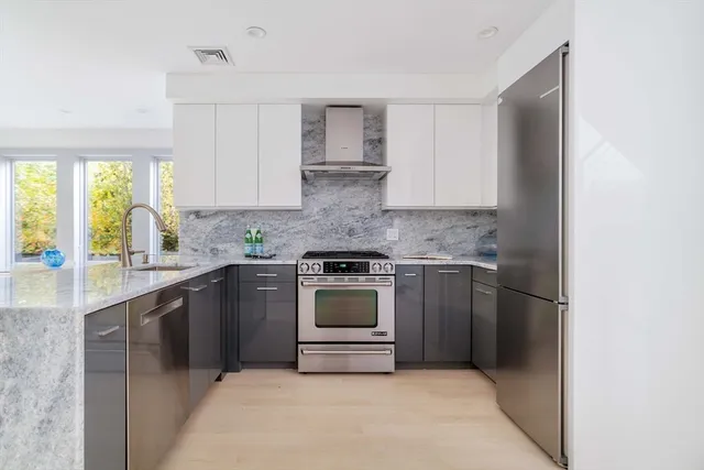 a kitchen with stainless steel appliances granite countertop a stove a sink and a refrigerator