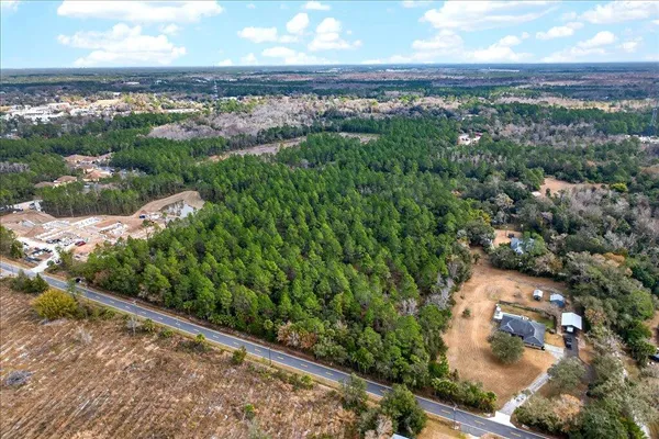 an aerial view of a residential houses with outdoor space and trees