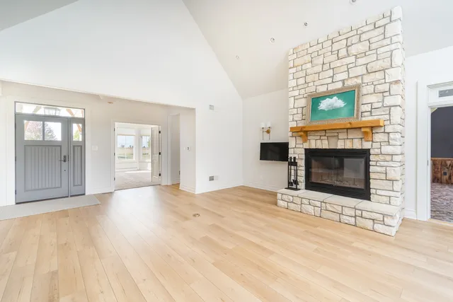 a view of an empty room with wooden floor and a fireplace