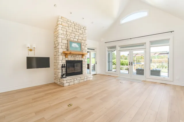 a view of an empty room with wooden floor fireplace and a window