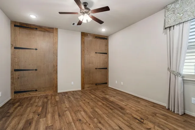 an empty room with wooden floor and a ceiling fan