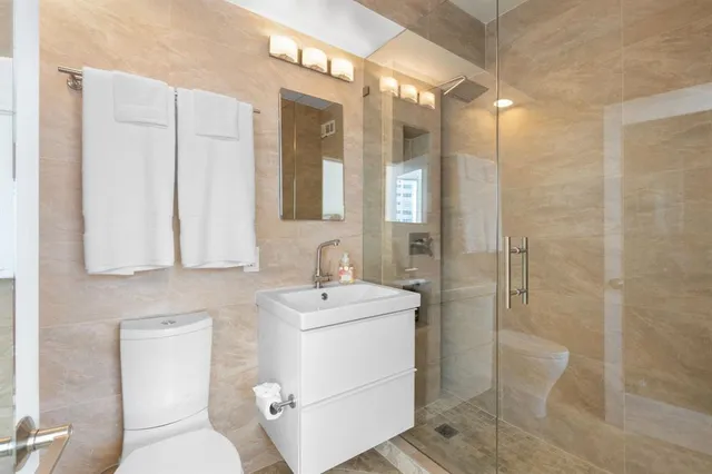 a bathroom with a sink a toilet a mirror and shower