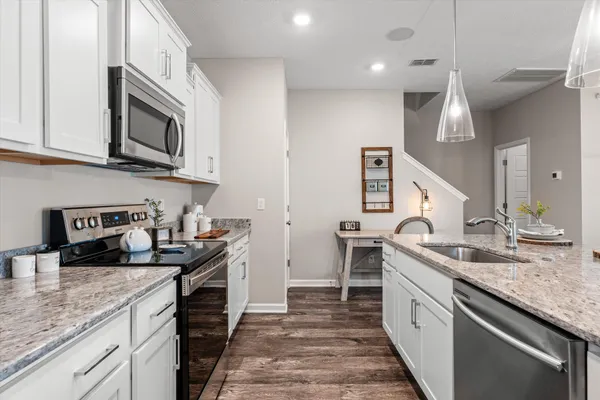 a kitchen with stainless steel appliances granite countertop a sink a stove and a wooden cabinets