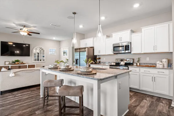 a kitchen with stainless steel appliances granite countertop a stove top oven a sink a stove a dining table and chairs