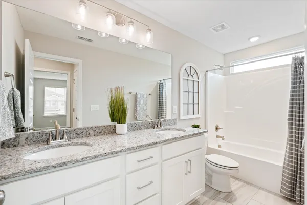 a bathroom with a granite countertop sink toilet a large mirror a bathtub and shower