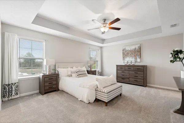 a spacious bedroom with a bed a dresser and a chandelier