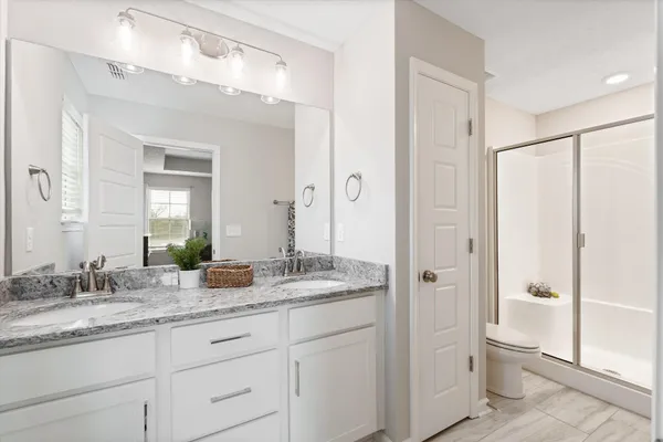 a bathroom with a granite countertop sink shower mirror and toilet