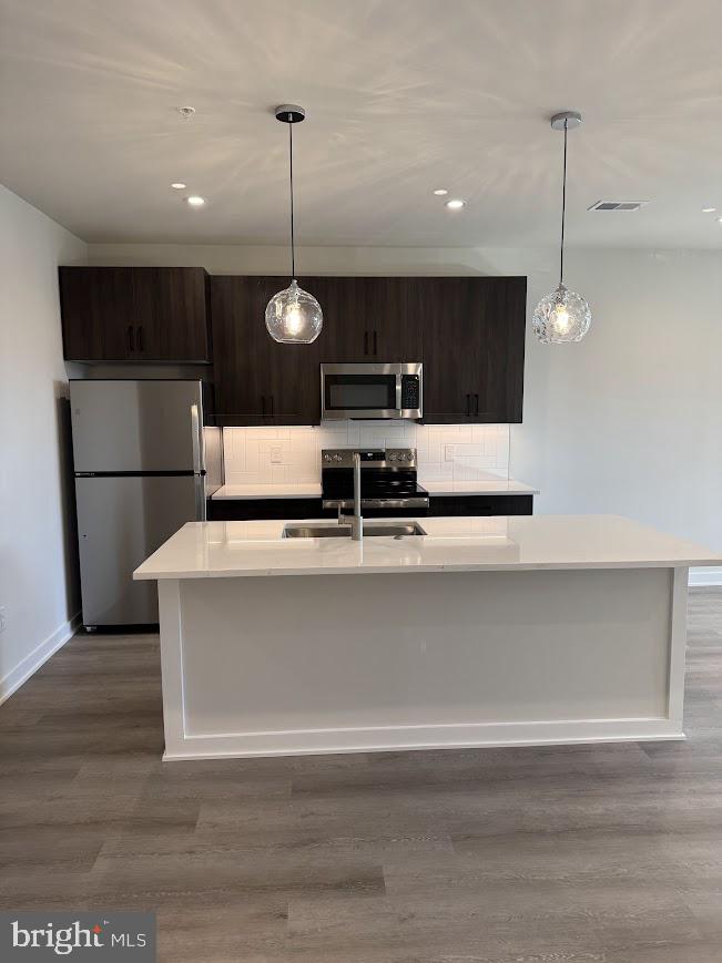 26 South York Road, Unit 103 Hatboro, PA 19040 - Photo 7 of 49 a kitchen with kitchen island stainless steel appliances a stove a refrigerator and a sink with wooden floor