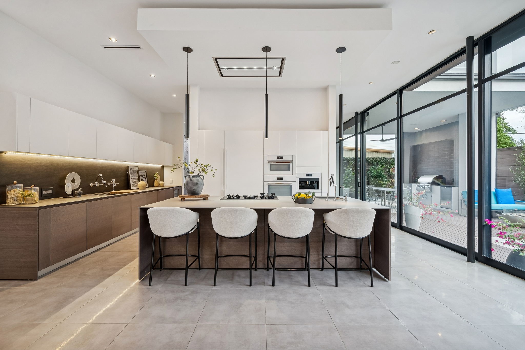 2332 Wroxton Road Houston, TX 77005 - Photo 4 of 50 Expansive floor-to-ceiling steel and glass windows flood the open living space with natural light, seamlessly connecting the indoors to the pool and private backyard. Sophisticated finishes, soaring ceilings, and a sleek fireplace set the stage for elegant entertaining, while the open layout ensures effortless flow to the kitchen and patio.