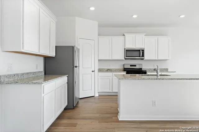 a kitchen with cabinets appliances a sink and a counter top space