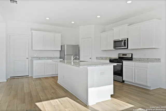 a kitchen with white cabinets a sink and appliances