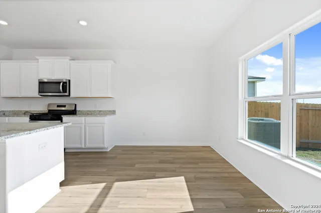 a large white kitchen with wooden floors and stainless steel appliances