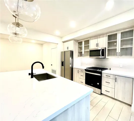 a kitchen with granite countertop a refrigerator and a stove top oven
