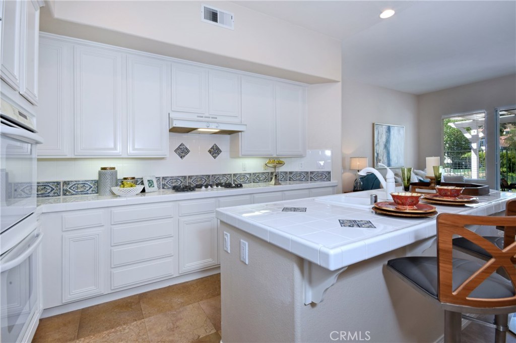 3619 Cll Joaquin Calabasas, CA 91302 - Photo 25 of 42 a kitchen with a stove a sink dishwasher and white cabinets with wooden floor