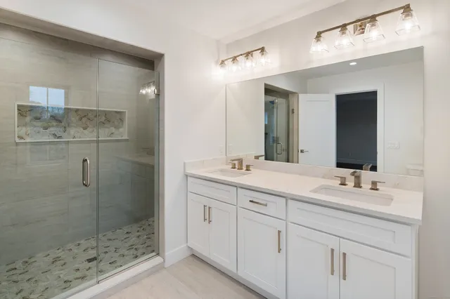 a bathroom with a double vanity sink mirror and shower