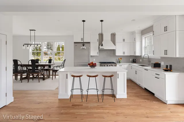 a kitchen with stainless steel appliances kitchen island granite countertop a table chairs stove and white cabinets