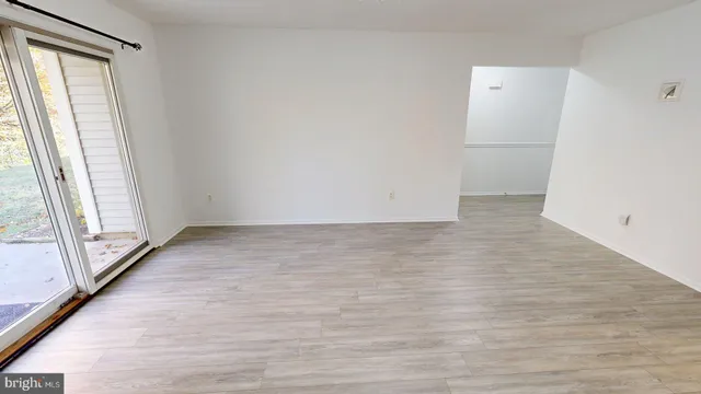 an empty room with wooden floor and window