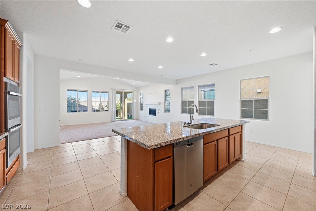250 Dedication Avenue Henderson, NV 89011 - Photo 67 of 67 Kitchen with wood finish cabinets, light stone counters, stainless steel appliances, vaulted ceiling, and open floor plan