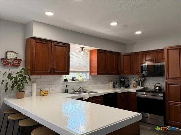 a kitchen with kitchen island granite countertop wooden cabinets and a refrigerator