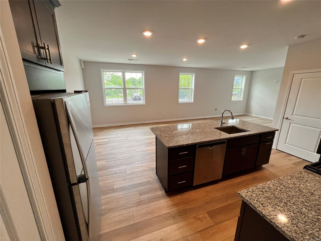 227 Tower Ridge Circle, Unit 227 Middletown, NY 10941 - Photo 3 of 16 Kitchen featuring a center island with sink, sink, light wood-type flooring, light stone counters, and stainless steel appliances