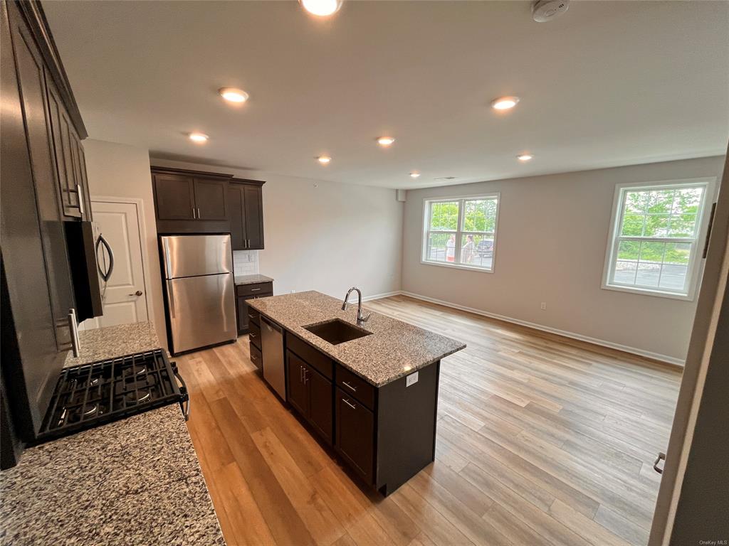 227 Tower Ridge Circle, Unit 227 Middletown, NY 10941 - Photo 4 of 16 Kitchen with light stone countertops, sink, a center island with sink, appliances with stainless steel finishes, and light wood-type flooring