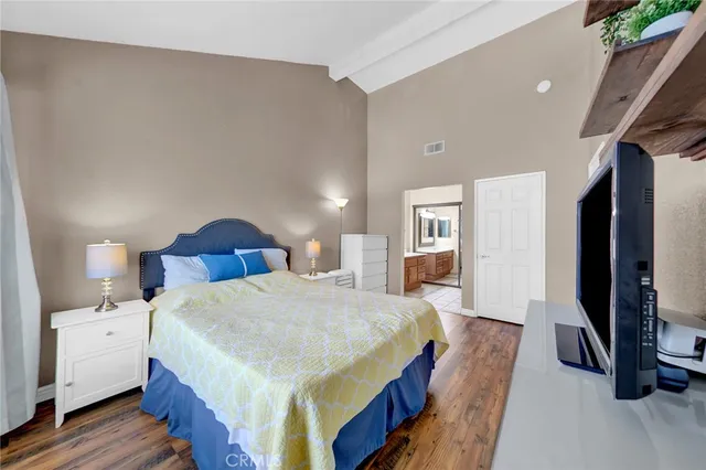 a spacious bedroom with a bed a mirror and dresser