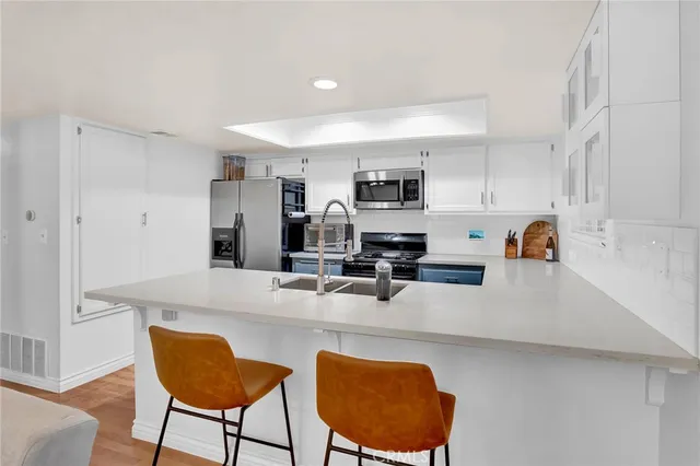 a kitchen with stainless steel appliances granite countertop a sink a stove a refrigerator cabinets and chairs