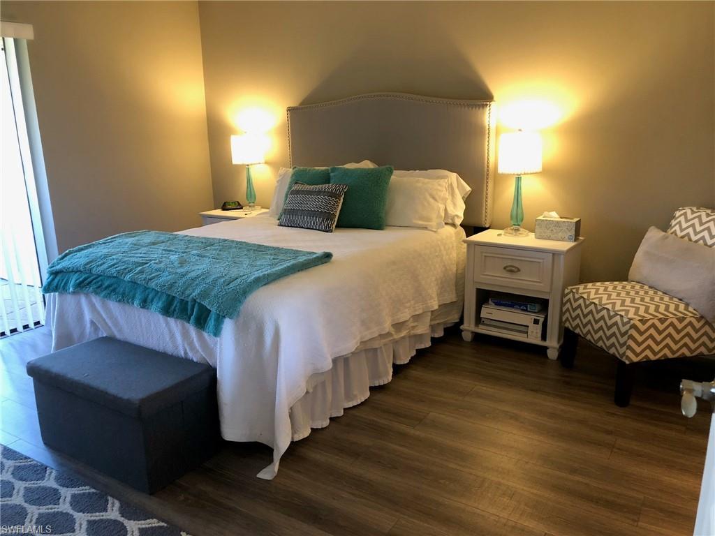 252 Pebble Beach Circle, Unit C103 Naples, FL 34113 - Photo 11 of 21 a bedroom with bed and wooden floor
