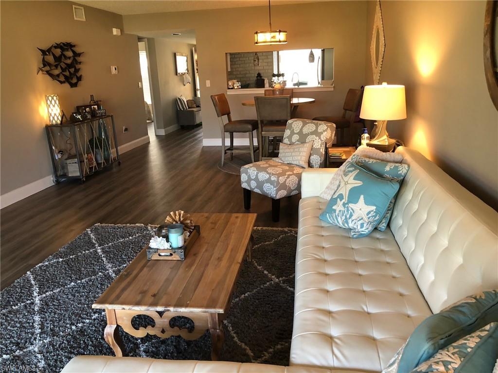 252 Pebble Beach Circle, Unit C103 Naples, FL 34113 - Photo 2 of 21 a living room with furniture and a lamp