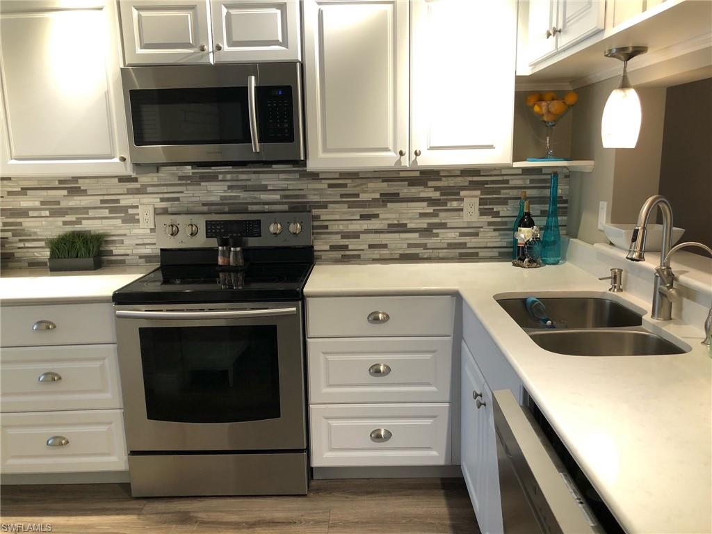 252 Pebble Beach Circle, Unit C103 Naples, FL 34113 - Photo 5 of 21 a kitchen with stainless steel appliances a stove microwave and sink