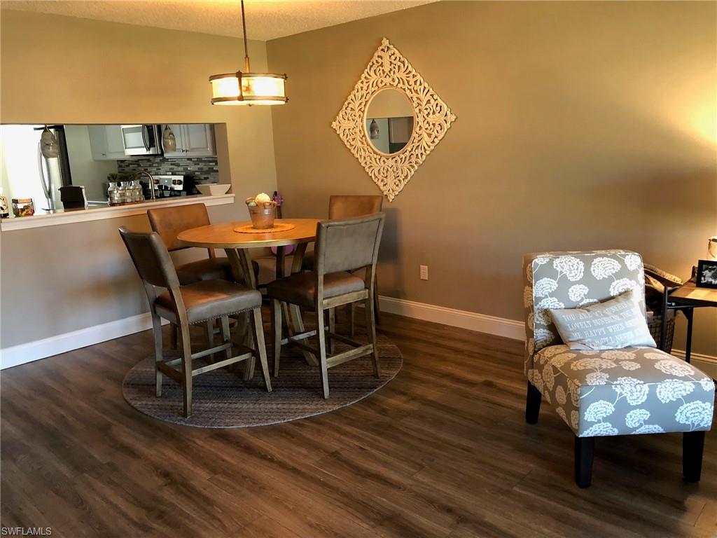 252 Pebble Beach Circle, Unit C103 Naples, FL 34113 - Photo 6 of 21 a dining room with furniture a chandelier and wooden floor