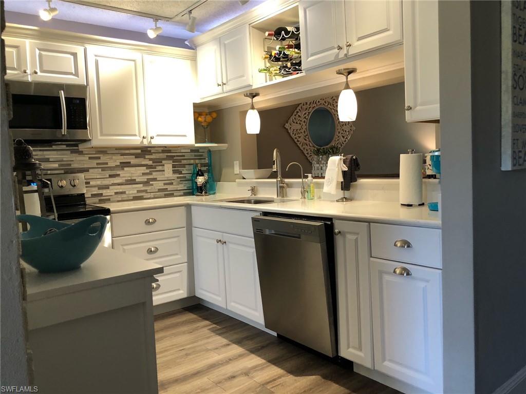 252 Pebble Beach Circle, Unit C103 Naples, FL 34113 - Photo 7 of 21 a kitchen with a sink cabinets and stainless steel appliances