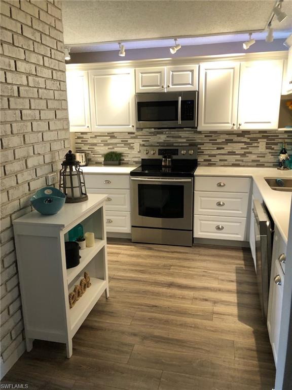 252 Pebble Beach Circle, Unit C103 Naples, FL 34113 - Photo 9 of 21 a kitchen with stainless steel appliances a stove and a microwave