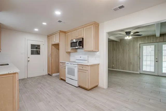 a view of kitchen with stainless steel appliances granite countertop a stove top oven a sink and a refrigerator