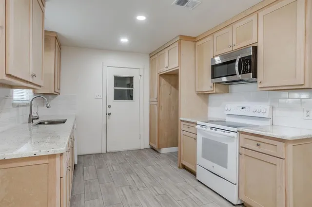 a kitchen with stainless steel appliances granite countertop a stove a sink and a microwave