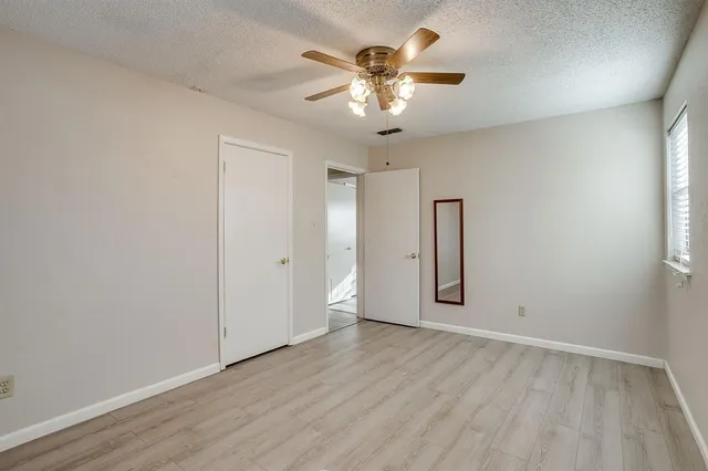 an empty room with wooden floor chandelier fan and windows