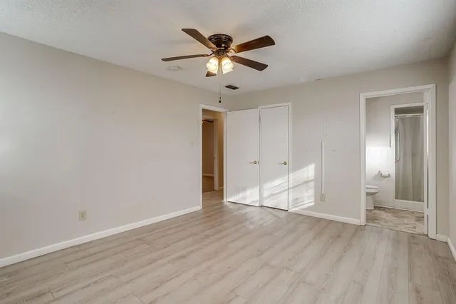 an empty room with wooden floor and ceiling fan
