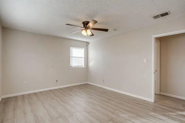 an empty room with a window and a fan
