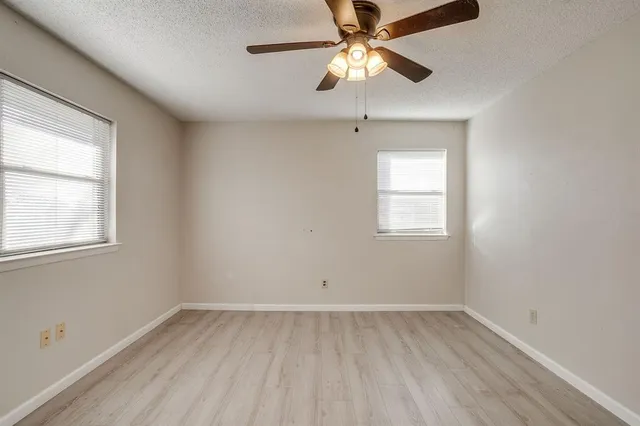 an empty room with a window and a fan