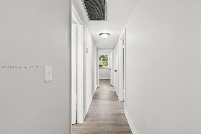 a view of a hallway with wooden floor and a bathroom