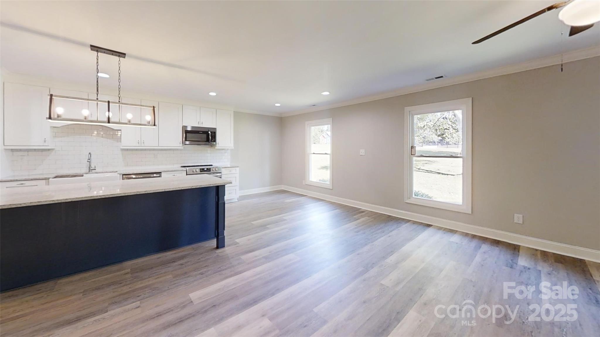 5406 Christopher Road Iron Station, NC 28080 - Photo 8 of 23 a large kitchen with stainless steel appliances kitchen island a large counter top and a wooden floor