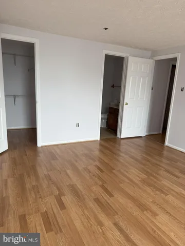 a view of an empty room with wooden floor and closet