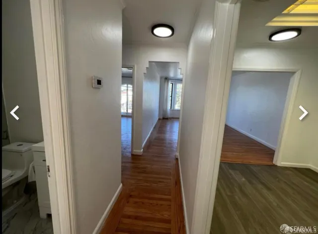a view of a hallway with wooden floor and staircase