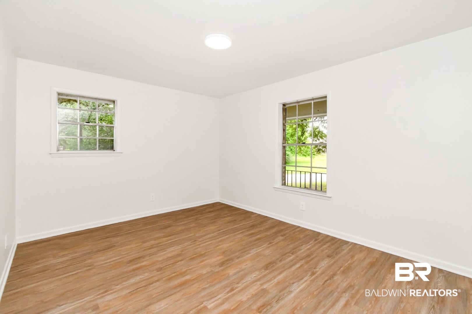 5217 Perin Road Mobile, AL 36693 - Photo 7 of 45 Spacious room featuring wood-finish flooring, white baseboards, and bright white walls